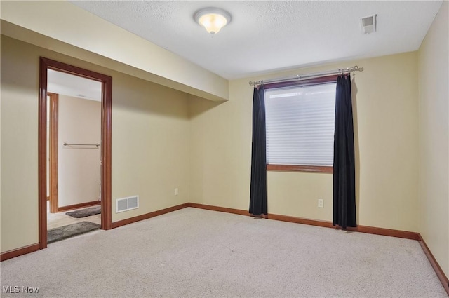 spare room featuring a textured ceiling and carpet flooring