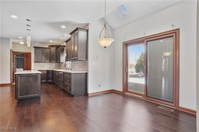 kitchen with dark hardwood / wood-style flooring, decorative light fixtures, a center island, and decorative backsplash