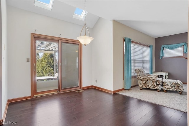 interior space featuring dark hardwood / wood-style flooring, vaulted ceiling with skylight, and plenty of natural light