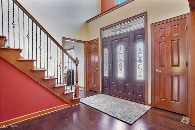 foyer entrance featuring wood-type flooring and a towering ceiling