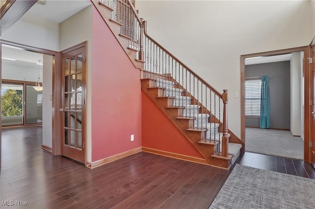 stairs with wood-type flooring and a high ceiling