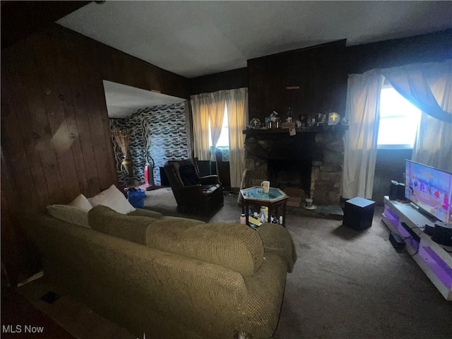 carpeted living room with a stone fireplace, wood walls, and a wealth of natural light