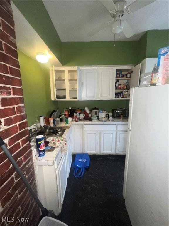 kitchen featuring white fridge, ceiling fan, and white cabinets