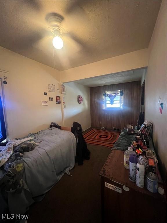 carpeted bedroom with wooden walls and ceiling fan