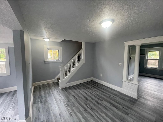 interior space with a healthy amount of sunlight, ornate columns, and dark wood-type flooring