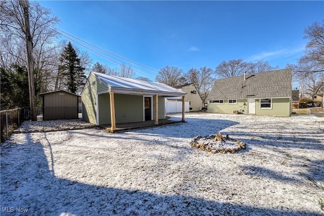 snow covered rear of property featuring a storage unit