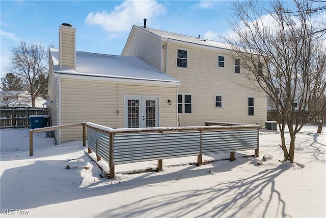 snow covered back of property featuring central AC unit and french doors