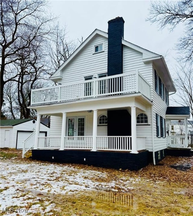 view of front of house with an outdoor structure, a garage, and a balcony