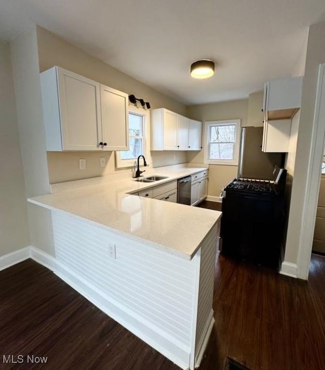 kitchen featuring white cabinetry, kitchen peninsula, sink, dark wood-type flooring, and appliances with stainless steel finishes