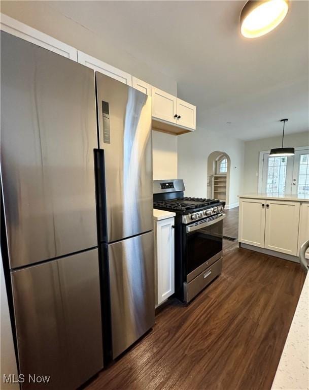 kitchen featuring white cabinetry, dark wood-type flooring, appliances with stainless steel finishes, and decorative light fixtures