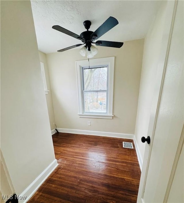 unfurnished room featuring ceiling fan, dark hardwood / wood-style floors, and a textured ceiling