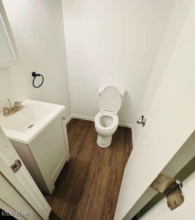 bathroom with toilet, vanity, and hardwood / wood-style floors