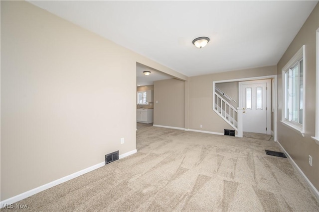 unfurnished living room featuring light carpet and a healthy amount of sunlight