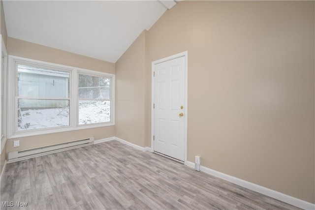 empty room with lofted ceiling, a baseboard heating unit, and light hardwood / wood-style flooring