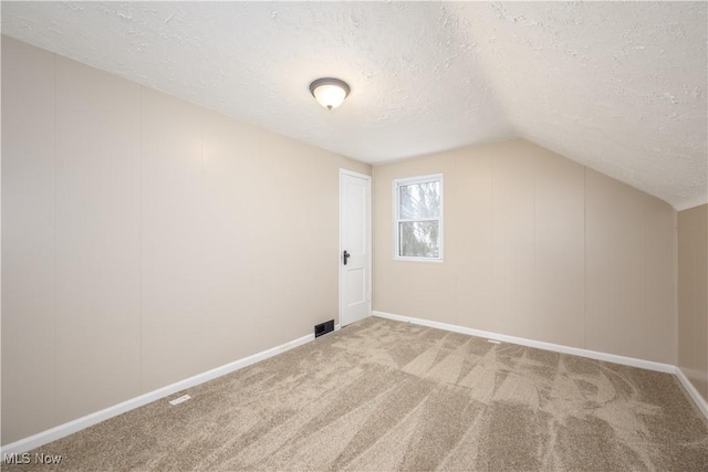 bonus room featuring carpet floors, lofted ceiling, and a textured ceiling