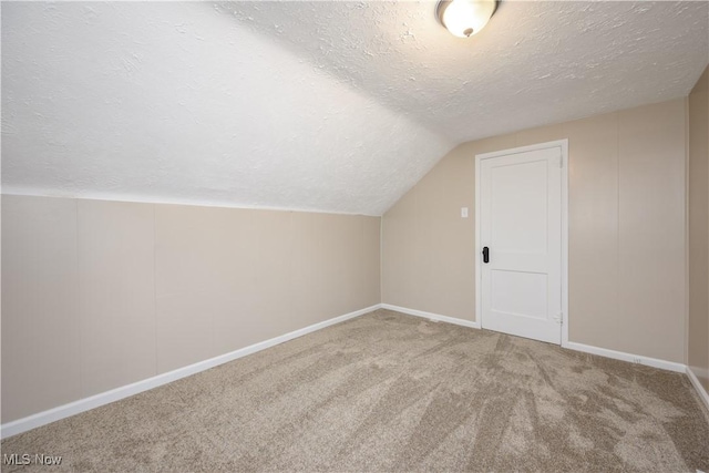 bonus room with carpet flooring, vaulted ceiling, and a textured ceiling