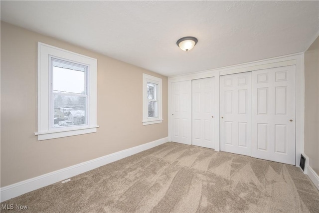 unfurnished bedroom with carpet and two closets