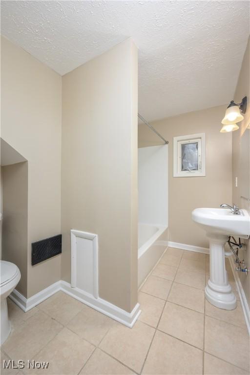 bathroom with tile patterned floors, toilet, and a textured ceiling