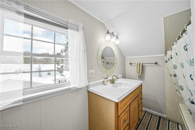 bathroom featuring lofted ceiling, shower / bath combo with shower curtain, vanity, and ornamental molding