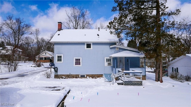 snow covered rear of property with a deck