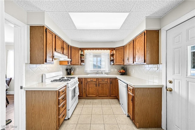 kitchen with white appliances, light tile patterned floors, sink, and a drop ceiling