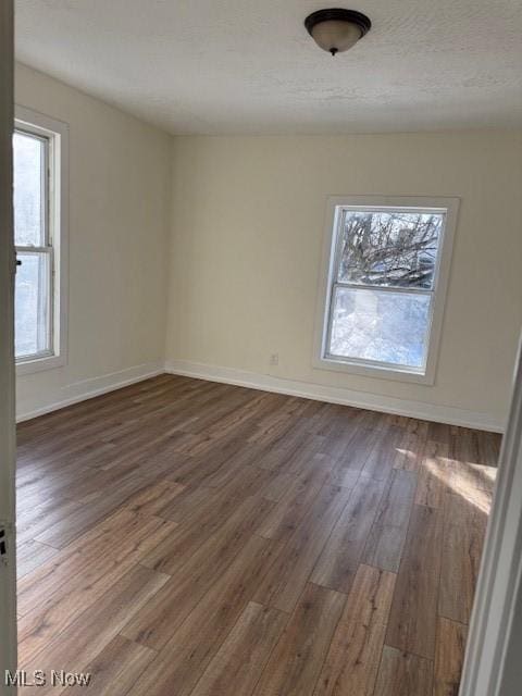 spare room with a textured ceiling and dark hardwood / wood-style flooring