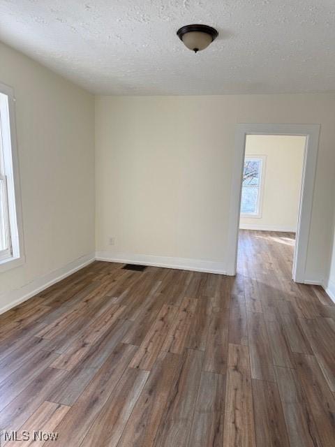 empty room with dark hardwood / wood-style flooring and a textured ceiling