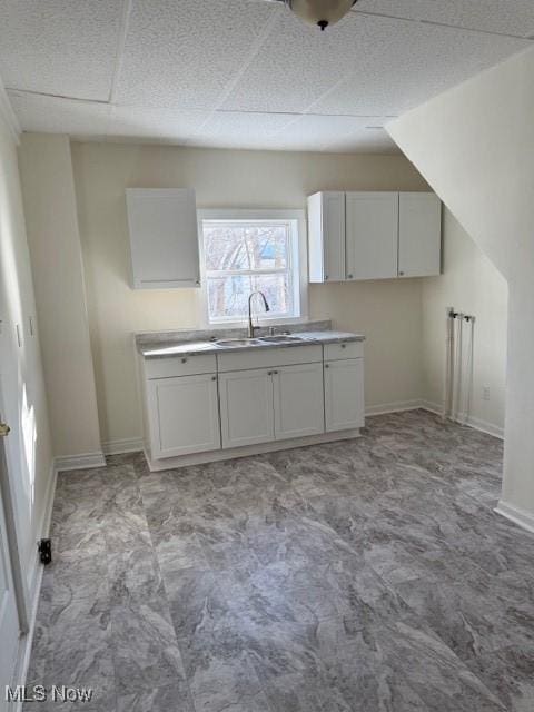 kitchen featuring sink, white cabinetry, and a drop ceiling