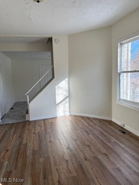 unfurnished living room with a textured ceiling and dark hardwood / wood-style floors