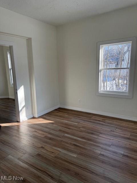 spare room with a textured ceiling and dark hardwood / wood-style flooring