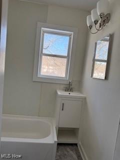 bathroom with a bathing tub, vanity, and a notable chandelier