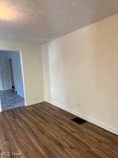 unfurnished room with dark wood-type flooring