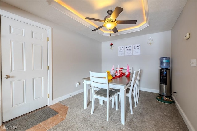 carpeted dining space featuring a tray ceiling and ceiling fan