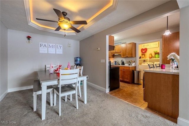 dining area featuring independent washer and dryer, light tile patterned flooring, ceiling fan, and a raised ceiling