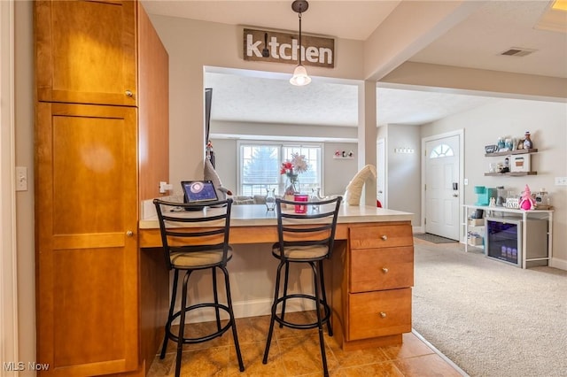 kitchen featuring a breakfast bar area, light colored carpet, and decorative light fixtures