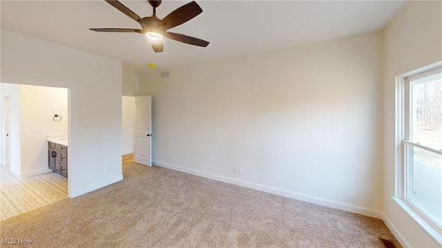 unfurnished bedroom with light carpet, ensuite bathroom, and ceiling fan