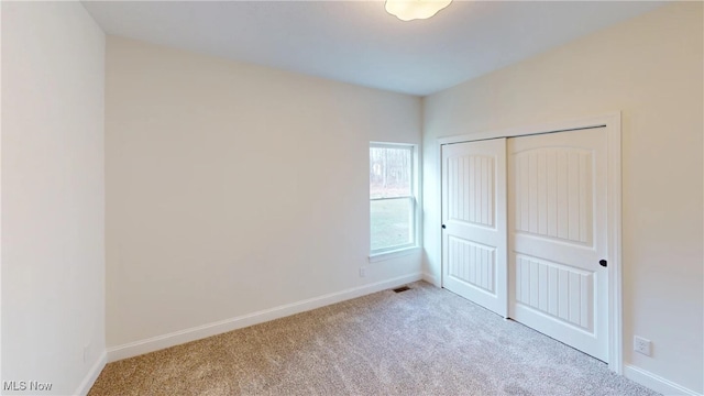 unfurnished bedroom featuring a closet and light colored carpet