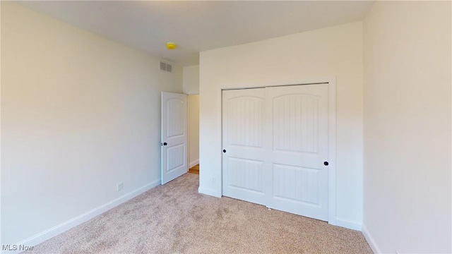 unfurnished bedroom featuring a closet and light colored carpet