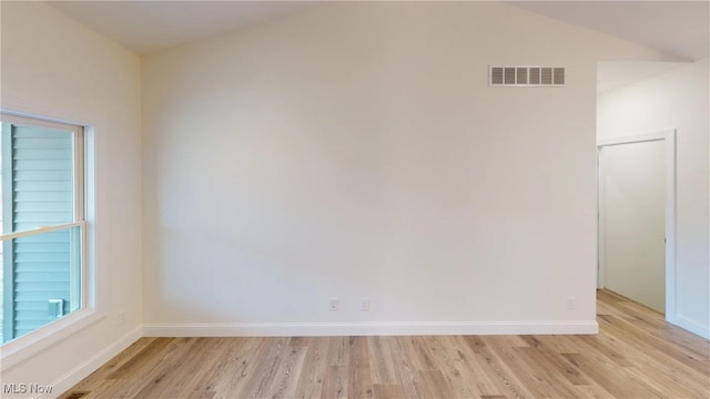 empty room featuring vaulted ceiling and light hardwood / wood-style floors