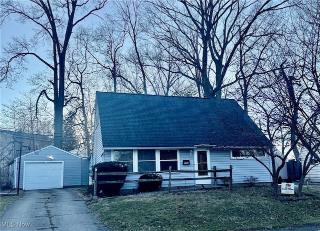 cape cod home with an outbuilding, a garage, roof with shingles, and aphalt driveway