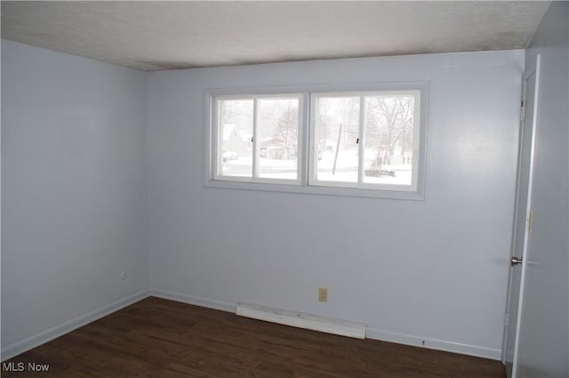 unfurnished room with dark wood-style floors, a baseboard radiator, and baseboards