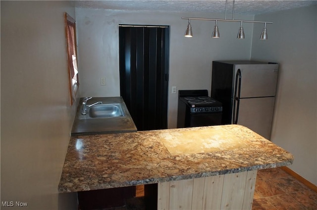 kitchen with black / electric stove, decorative light fixtures, freestanding refrigerator, a sink, and baseboards