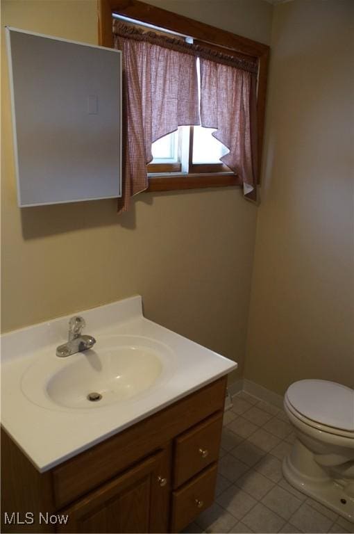 bathroom featuring baseboards, vanity, toilet, and tile patterned floors