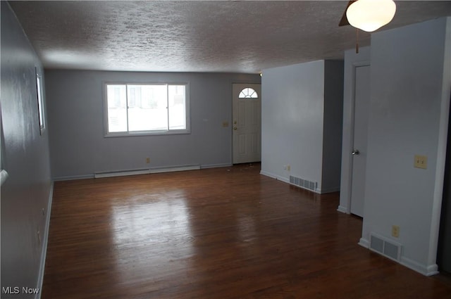 unfurnished room with dark wood-type flooring, baseboard heating, visible vents, and baseboards