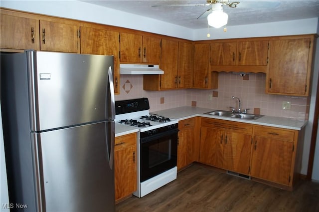 kitchen with range with gas stovetop, light countertops, freestanding refrigerator, a sink, and under cabinet range hood