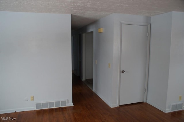 unfurnished room featuring dark wood-style floors, visible vents, and a textured ceiling