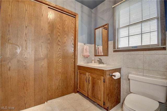 bathroom featuring toilet, tile walls, tile patterned flooring, and vanity