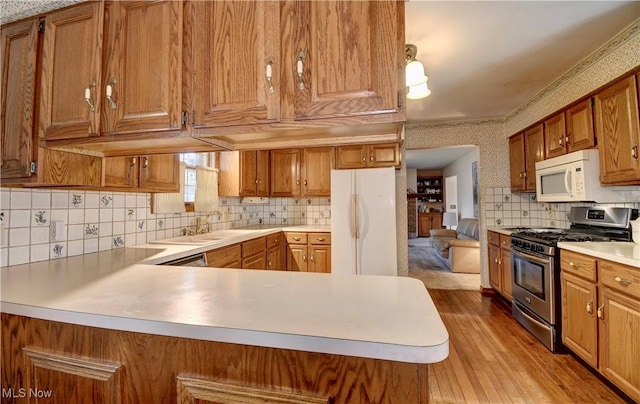 kitchen featuring kitchen peninsula, light hardwood / wood-style floors, sink, white appliances, and crown molding