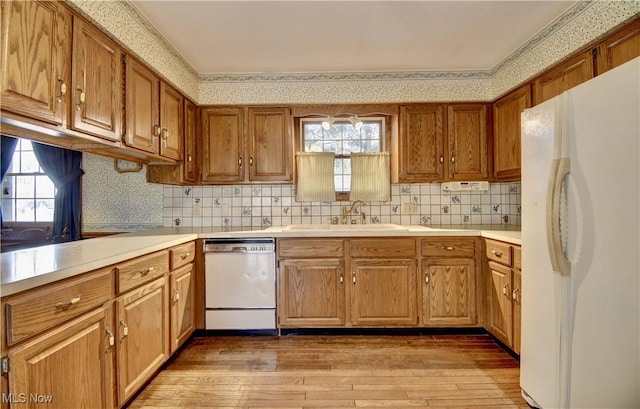 kitchen featuring sink, white appliances, tasteful backsplash, and light hardwood / wood-style floors