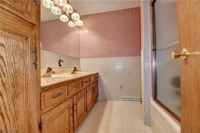 bathroom with tile walls, vanity, bath / shower combo with glass door, and tile patterned floors